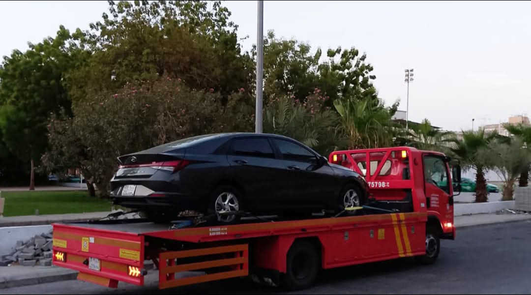 Flatbed towing a black car